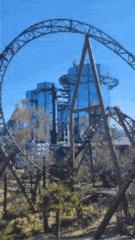 a roller coaster in a park with a building in the background