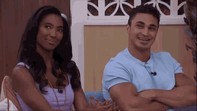 a man and a woman are sitting on a couch with their arms crossed