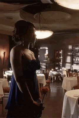 a woman in a blue dress is holding a flower in a restaurant .