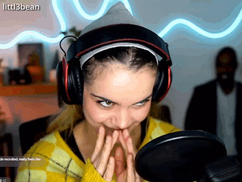 a woman wearing headphones is making a funny face in front of a microphone and the name littl3bean is on the screen