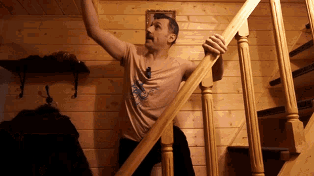 a man in a pink shirt with a bird on it is standing on a set of wooden stairs