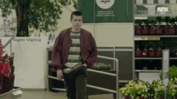 a man in a striped shirt is walking in front of a sign that says " hagen utgang "
