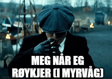 a man in a suit and hat is smoking a cigarette and says meg nar eg roykjer ci myrvac