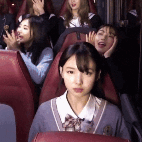 a girl in a school uniform is sitting in a red seat