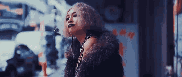 a woman in a fur coat is standing on a city street .