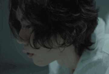 a close up of a person 's face with curly hair and a white shirt .