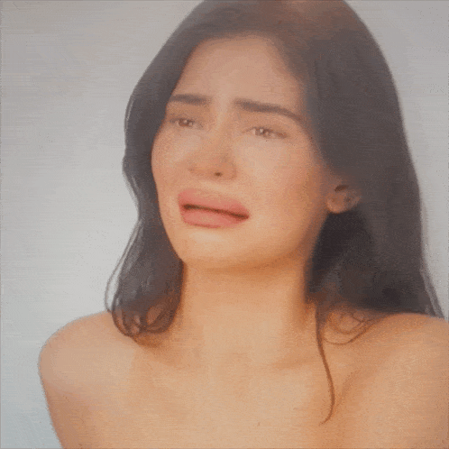 a woman without a shirt is crying with her mouth open .