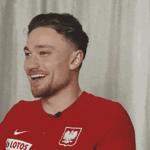 a man wearing a red shirt with the word lotos on the front