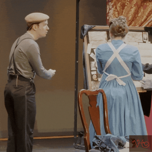 a woman in a blue dress is standing next to a man