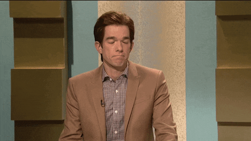 a man in a suit and plaid shirt is standing in front of a wall