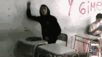 a man in a black hoodie is standing in front of a white board with the word gimp written on it .