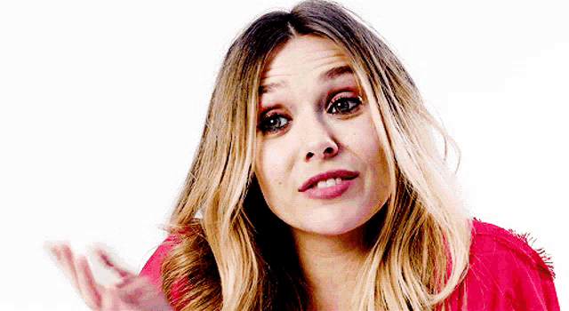 a woman with long blonde hair is wearing a red shirt and making a face .