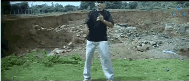 a man in a black shirt and white pants is standing in a field