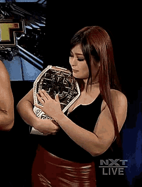 a woman is holding a wrestling championship belt .