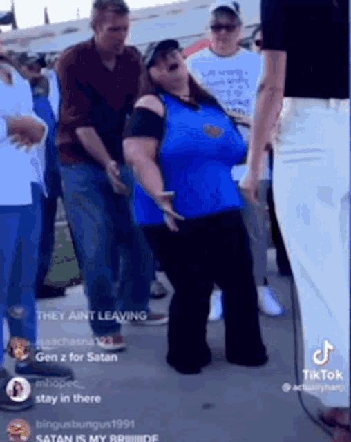 a woman in a blue shirt is dancing in front of a crowd of people .