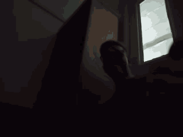 a dark room with a staircase and a window