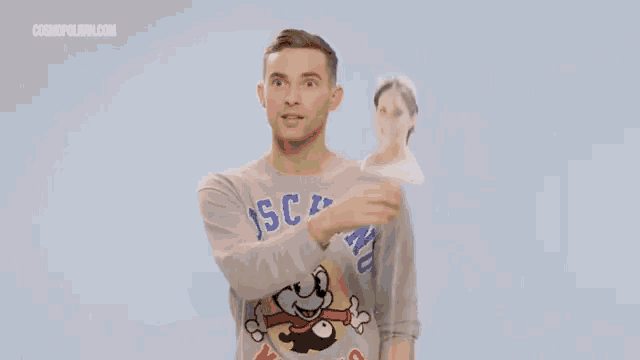 a man wearing a felix the cat sweater is taking a selfie with a woman behind him .