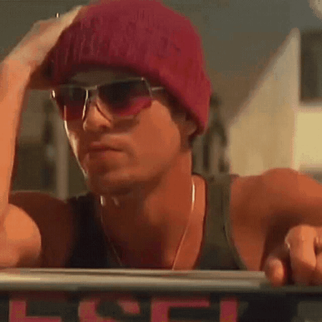 a man wearing a red beanie and sunglasses is looking out of a car window