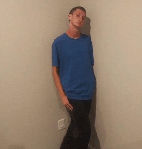 a man in a blue shirt stands in a corner