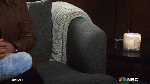 a person sitting on a couch with a candle and a nbc logo
