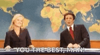 a man and a woman are sitting in front of a map of the world and a sign that says `` you the best man '' .
