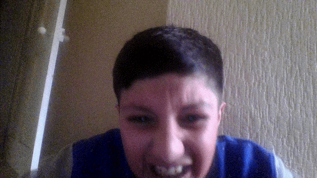 a young boy wearing a blue sweater is making a funny face