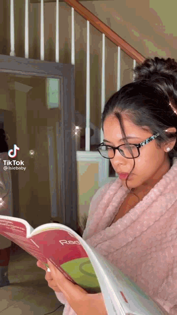 a woman wearing glasses is reading a book titled physics