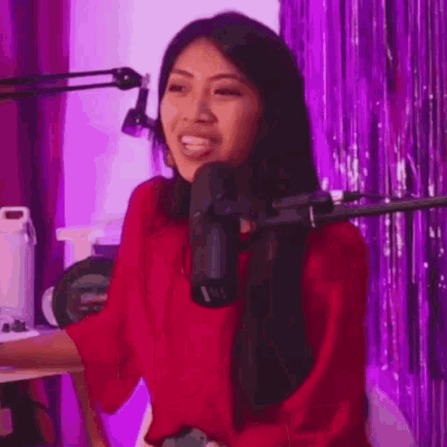 a woman in a red sweater is talking into a microphone .