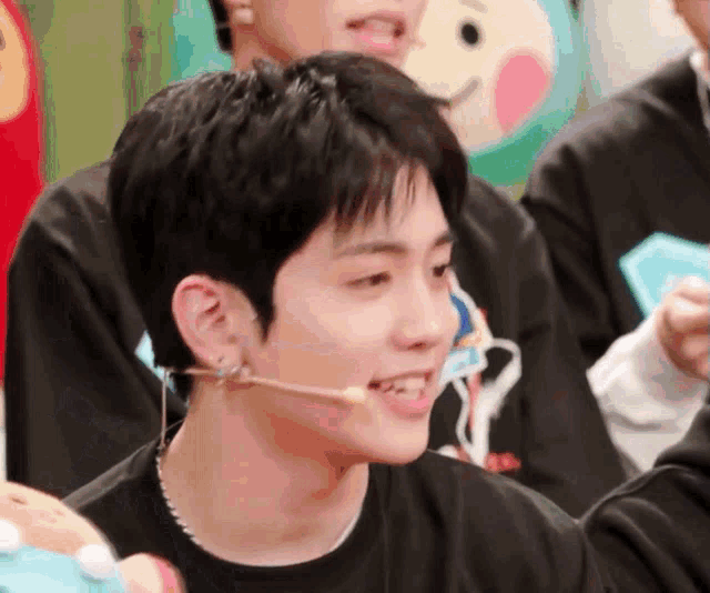 a young man wearing a black shirt and a microphone in his mouth