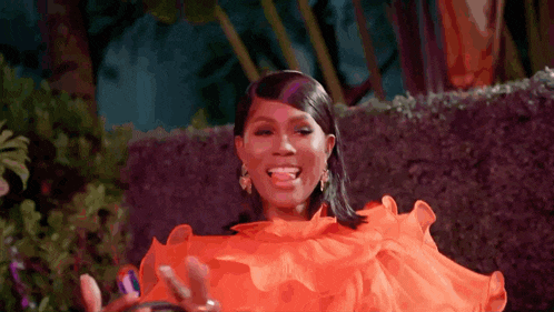 a woman wearing an orange dress is sticking her tongue out .
