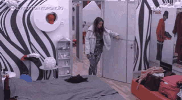 a woman opens a door in a room with a zebra print wall