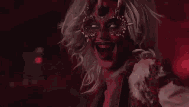a woman in a devil costume with horns is holding a red object .