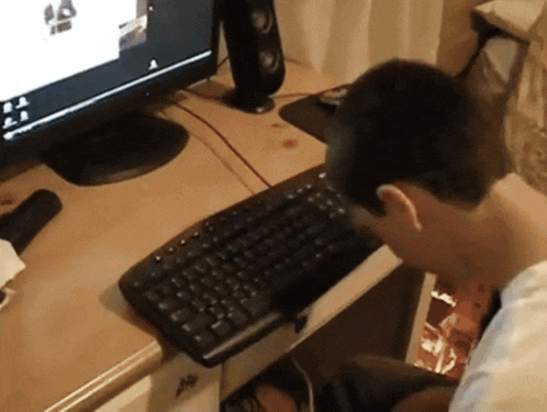 a person sitting at a desk with a keyboard and a monitor with the letter a on it
