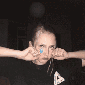 a girl is crying with tears coming out of her eyes in a dark room .