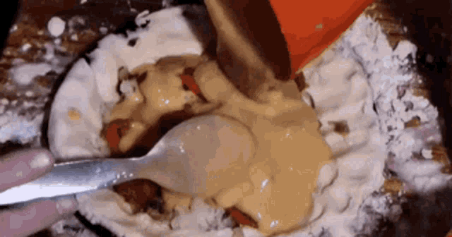 a person is using a spoon to stir a sauce in a bowl .