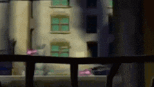 a blurry picture of a building with a balcony in the foreground and a window in the background .