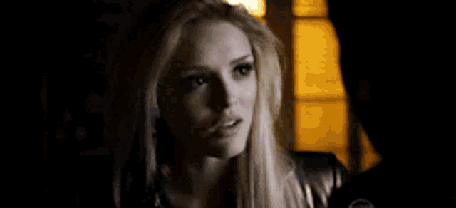 a woman is standing next to a man in a dark room and looking at the camera .