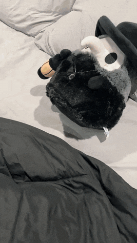 a stuffed animal laying on a bed with a blanket