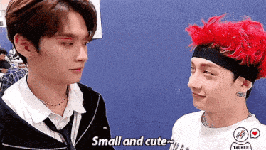 two young men are looking at each other and one of them has red hair and the other has black hair .