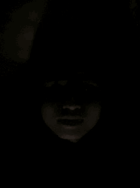 a close up of a person 's face in the dark with a hood on .