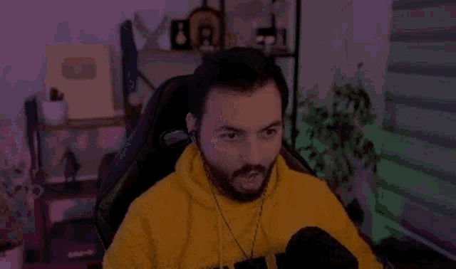 a man with a beard is sitting in a chair wearing headphones and looking at the camera .