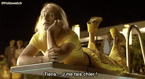 a man in a yellow shirt is laying on a table and says " tiens ... j'me fais chier "