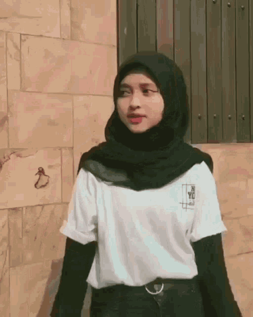 a woman wearing a hijab and a white shirt with the word yc on the front