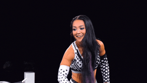 a female wrestler in a black and white polka dot top is smiling