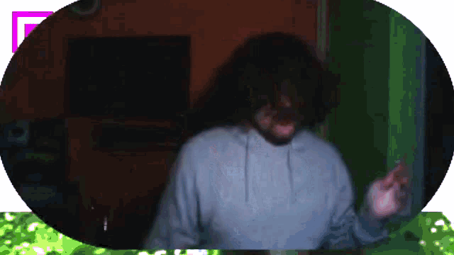 a man wearing a grey hoodie is standing in a dark room