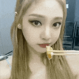 a close up of a girl eating food with chopsticks .