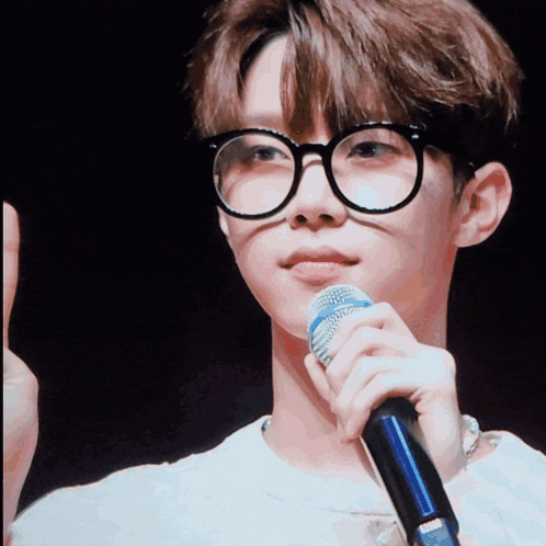 a man wearing glasses is holding a microphone