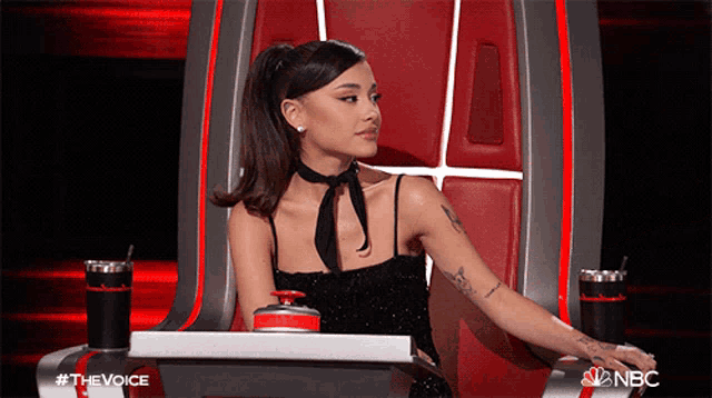 a woman in a black dress is sitting in a chair with a nbc logo in the corner