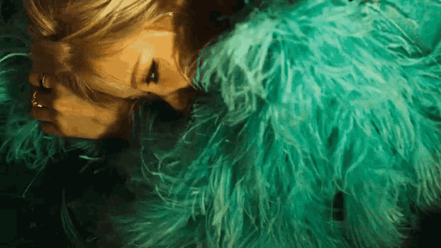 a woman wearing a green fur coat with a gold ring on her finger