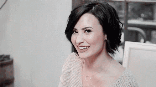 a close up of a woman wearing a sweater and necklace smiling .